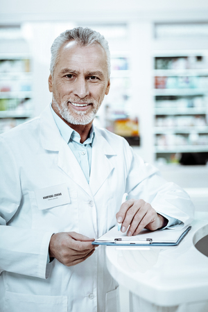 Delighted pensioner looking straight at camera, working in drug storeの写真素材