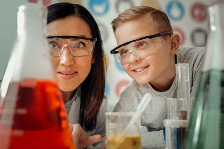 Waiting for results. Cheerful international female raising eyebrows while enjoying chemical experimentの写真素材