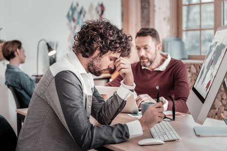 Difficult task. Serious brunette bowing head while having pause after workの写真素材