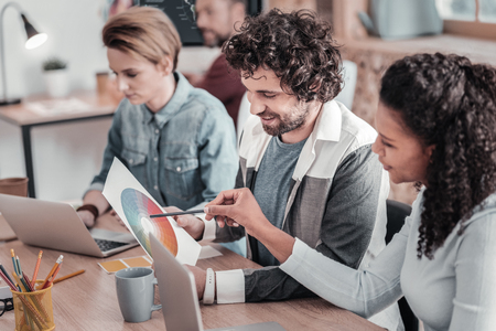 Kind male person keeping smile on his face while looking at color mapの写真素材