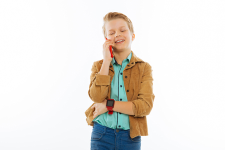 Mobile communication. Cute cheerful boy smiling while talking on the phoneの写真素材