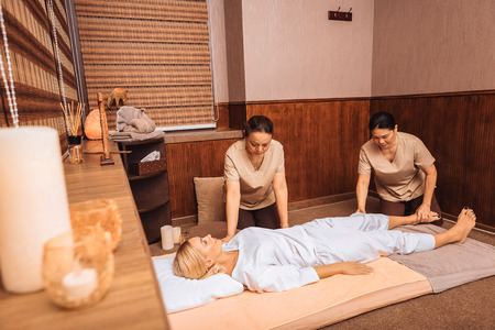 Professional cooperation. Two professional masseuses working together in the spa while doing the massageの写真素材