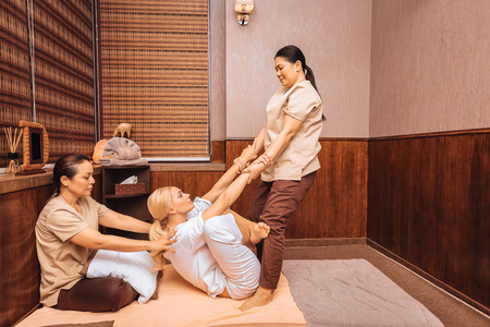 Massage technique. Nice good looking woman looking at her masseuse while being pushed from the backの写真素材