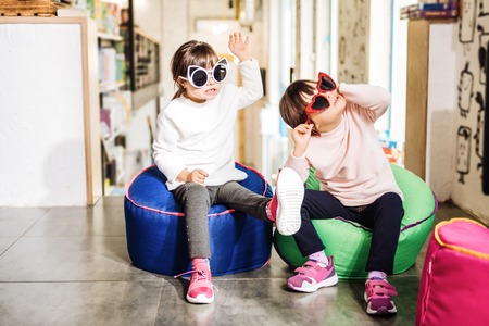 Pink sneakers. Twins wearing bright pink sneakers and funny sunglasses while playing togetherの写真素材