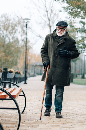 Heart attack. Handsome retirement looking aside while going to sit on benchの写真素材