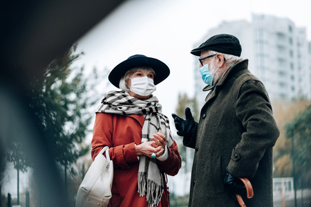Keep attention. Emotional grey-haired man standing in semi position and actively gesticulating during talkの写真素材