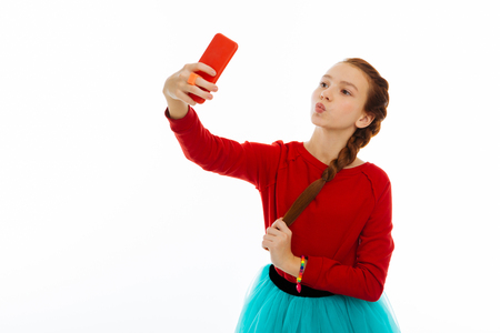 So beautiful. Nice cute girl holding her smartphone while posing for a selfieの写真素材