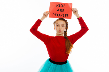 Read this. Cute pretty girl standing against white background while showing you a sheet of paperの写真素材