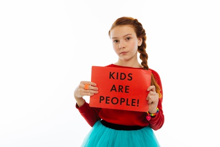 This is important. Serious nice girl showing a sheet of paper while defending children rightsの写真素材