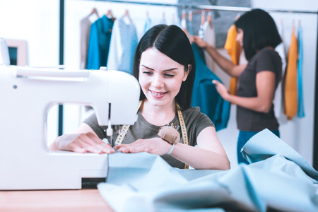 New order. Talented hardworking seamstress sewing a dress working with sewing machineの写真素材