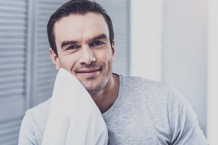 Good-looking male model feeling happiness while taking care of his skinの写真素材