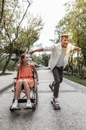 Sporty mood. Active young man keeping smile on his face while standing on his longboardの写真素材