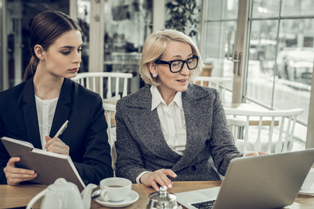 Female boss. Young attentive secretary feeling responsible while listening to her successful female bossの写真素材