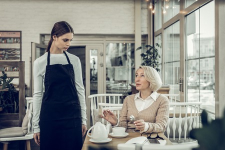 Unsatisfied with service. Elegant blonde-haired woman feeling unsatisfied with service in cafeteriaの写真素材