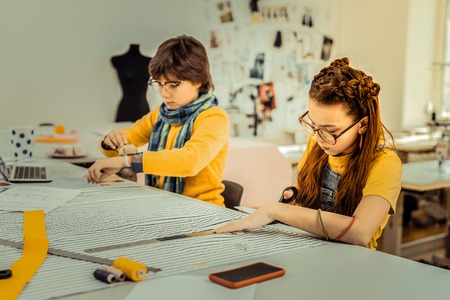 Drafting pattern. Talented creative children of fashion designer drafting patterns for their motherの写真素材