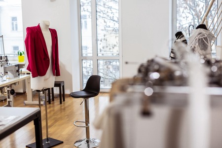 Red jacket. Beautiful red jacket for women hanging on a dummy in a center of a fashion studioの写真素材