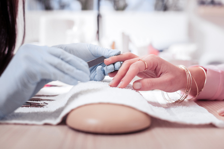 Perfect shape. Close up of a nail file being in use while correcting the shape of the nailの写真素材