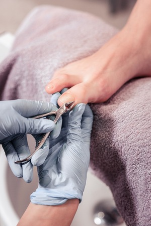 Professional instrument. Close up of nail clippers being in use while doing professional pedicure