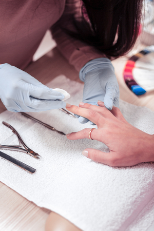 Natural nails. Top view of a process of a nail polish removing process from a female handの写真素材