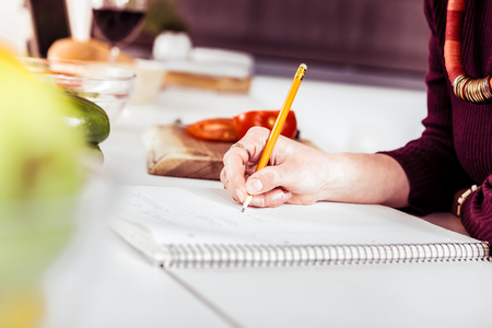 To do list. Busy woman leaning on table while creating plan for shoppingの写真素材