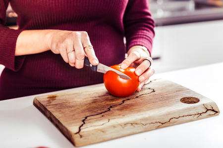 Sharp knife. Cute housewife being in kitchen while cooking saladの写真素材