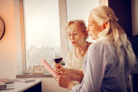 Nice aged women looking together at the picture while discussing itの写真素材