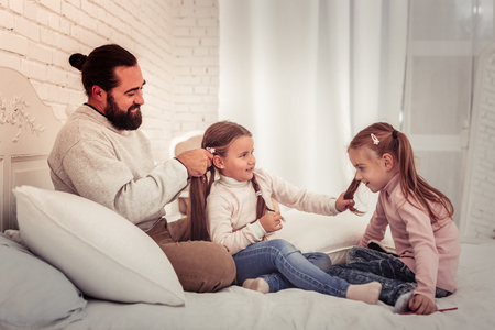 Long hair. Nice cute girl holding her sisters hair while having her hairstyle doneの写真素材