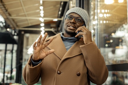Dark-eyed businessman. Dark-eyed businessman speaking on the phone with his colleague while waiting for himの写真素材