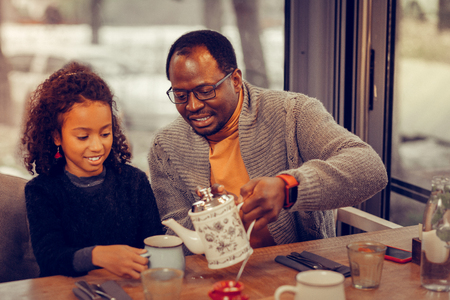 Tea in cafeteria. Loving father and cute little daughter drinking tasty tea in cafeteria togetherの写真素材