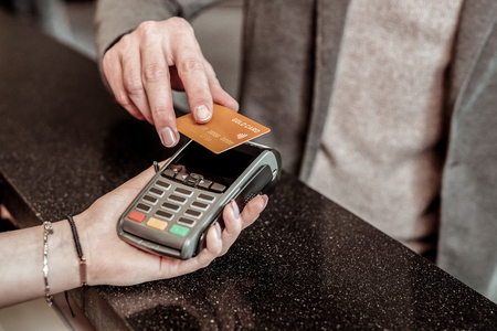 Modern technologies. Close up of male hand that holding card while choosing online bankingの写真素材