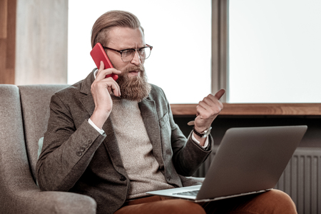 Listen to me. Professional manager staring at computer while talking per telephoneの写真素材