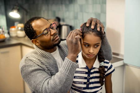 Fixing hairstyle. Loving father wearing grey cardigan fixing hairstyle of his beautiful daughterの写真素材