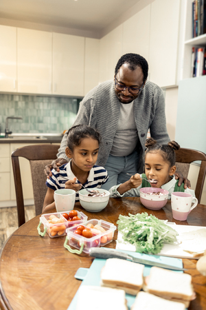 Tasty breakfast. Two cute beautiful twins having tasty breakfast before going to school sitting in the kitchenの写真素材