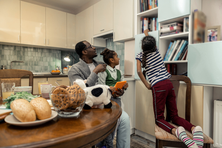 Reading with father. Cute little daughters taking books while reading with their caring fatherの写真素材