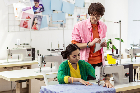 Busy. Two young asian fashion designers looking busy while working with fabricの写真素材