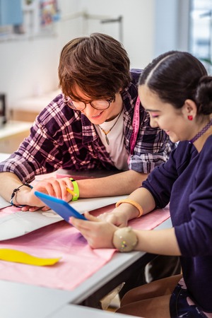 Good idea. Young beautiful female asian designer and her colleague looking contented while looking at the photos on a fashion siteの写真素材