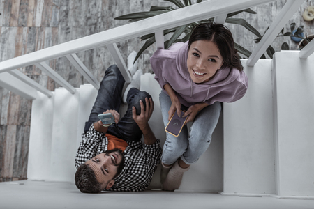 Shopping online. Modern young couple shopping online using their phones while sitting on stairsの写真素材