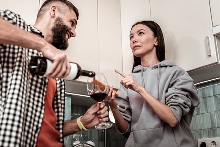 Drinking wine. Dark-eyed girlfriend telling about her day while drinking wine with her manの写真素材