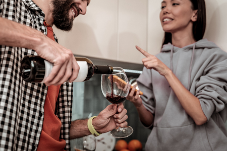 Having conversation. Young loving happy couple having conversation while drinking wine at homeの写真素材