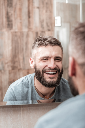 Joyful positive man smiling to his reflection while feeling refreshedの写真素材