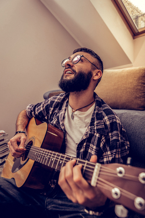 Creative art. Delighted nice man using a guitar while composing his own musicの写真素材