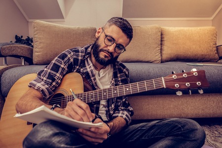 Creative ideas. Serious concentrated man taking notes while composing musicの写真素材