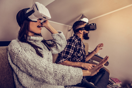 Modern tech. Positive emotional couple using virtual reality glasses while trying new technologiesの写真素材