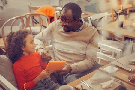 Father wearing glasses giving tablet to his girl wishing to play games