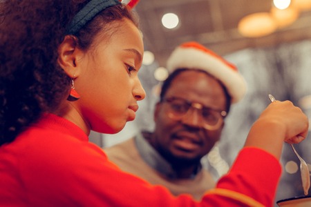 Cocoa with dad. Close up of appealing daughter drinking cocoa with marshmallows near her dadの写真素材