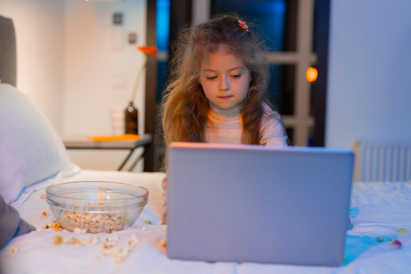 Playful mood. Cute long-haired girl with a bright hairpin looking pleased while playing on a laptopの写真素材