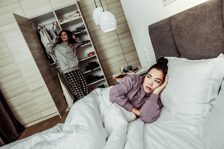 Cannot fall asleep. Dark-eyed angry roommate cannot fall asleep while hearing phone conversationの写真素材