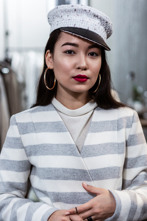 Red lipstick. Young asian beaming woman with red lipstick wearing a trendy headwear looking contentedの写真素材