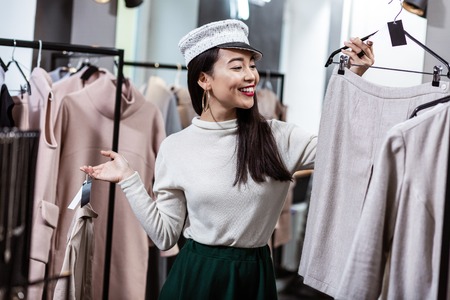 New skirt. Brunette asian beautiful woman wearing a nice headwear choosing a skirt