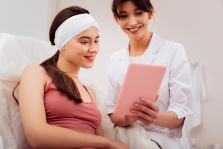 So beautiful. Happy excited woman smiling while looking at the photo on the tablet screenの写真素材